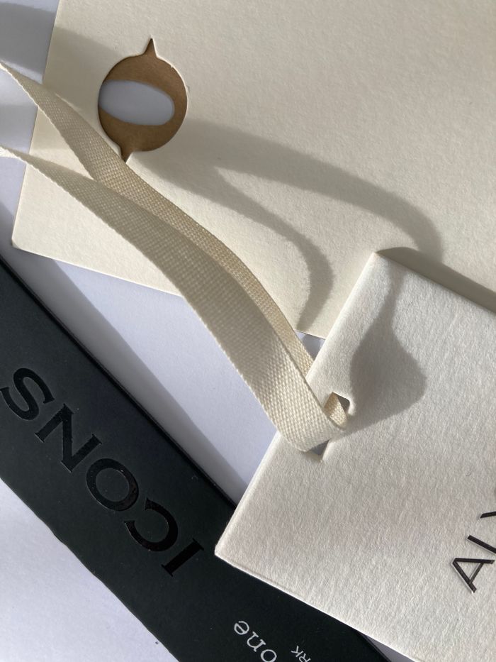 Aesthetic flat lay of various tags and paper with elegant design in soft lighting.