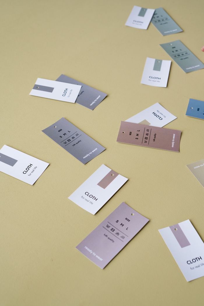 Scattered clothing tags on a neutral background, showcasing colors and designs.